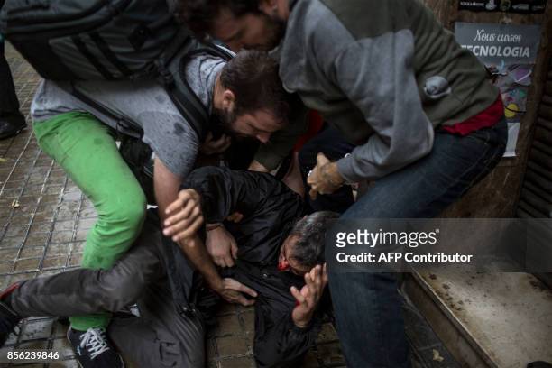 People help a man injured by a rubber bullet fired by Spanish police officers outside the Ramon Llull polling station in Barcelona October 1, 2017...