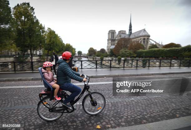 Cyclists ride past Notre Dame Cathedral during a "car free" day in Paris on October 1, 2017. Parisians were encouraged to roller-blade, bike or...