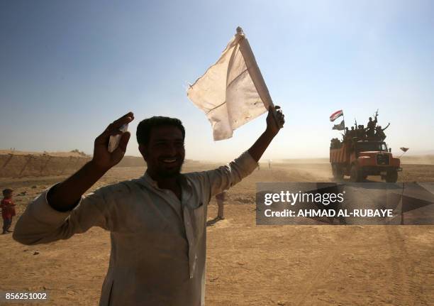 An Iraqi man, from a neighbouring village, waves a white flag as Iraqi forces and fighters from the Hashed al-Shaabi advance towards the Islamic...