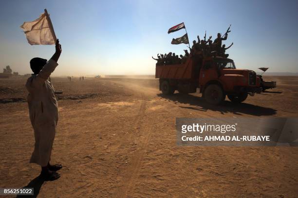 An Iraqi man, from a neighbouring village, waves a white flag as Iraqi forces and fighters from the Hashed al-Shaabi advance towards the Islamic...
