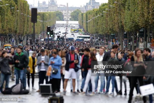 People walk down the Champs Elysees avenue during a "car free" day in Paris on October 1, 2017. Parisians were encouraged to roller-blade, bike or...