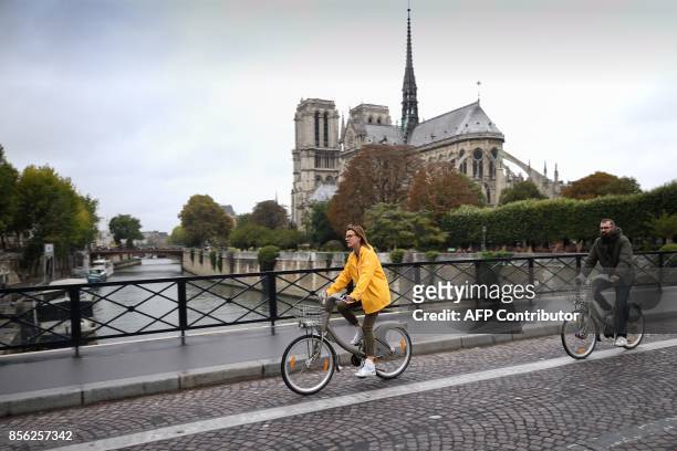 Cyclists ride past Notre Dame Cathedral during a "car free" day in Paris on October 1, 2017. Parisians were encouraged to roller-blade, bike or...