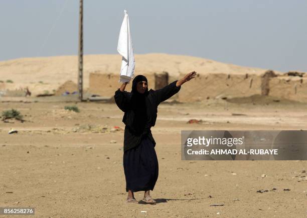 An Iraqi woman, from a neighbouring village, waves a white flag as Iraqi forces and fighters from the Hashed al-Shaabi advance towards the Islamic...
