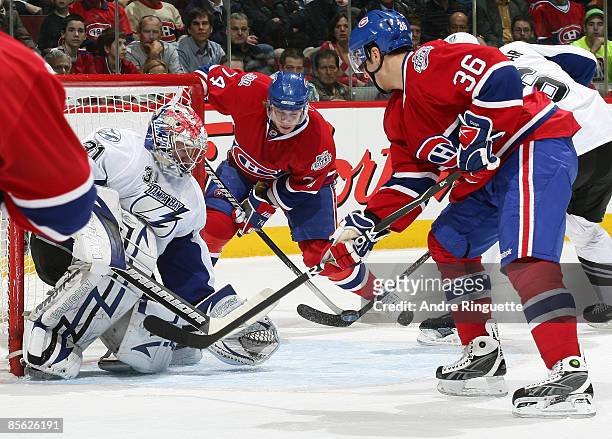 Sergei Kostitsyn and Matt D'Agostini of the Montreal Canadiens swing at a rebound as Karri Ramo of the Tampa Bay Lightning guards his net at the Bell...