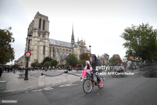 Cyclist rides past Notre Dame Cathedral during a "car free" day in Paris on October 1, 2017. Parisians were encouraged to roller-blade, bike or...