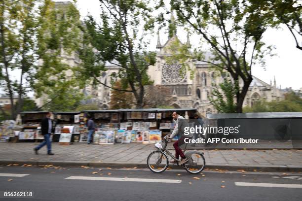Cyclist rides past Notre Dame Cathedral during a "car free" day in Paris on October 1, 2017. Parisians were encouraged to roller-blade, bike or...