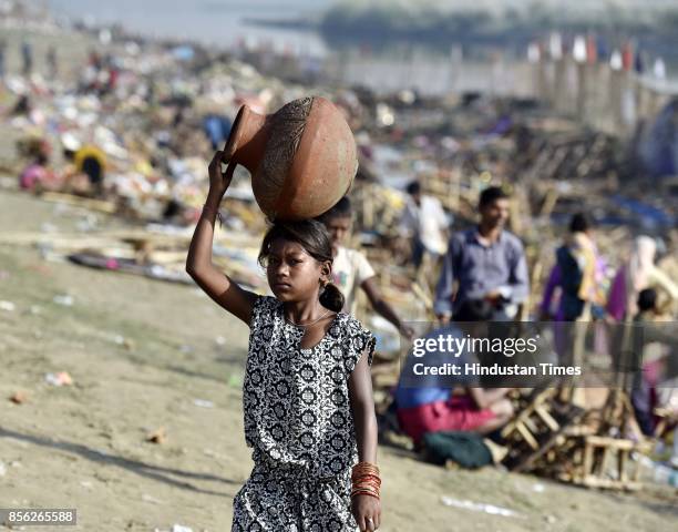 Girl carries an earthen pot she found after the immersion of Goddess Durga idols after the celebration of 9-day long festival of Durga Puja at Yamuna...