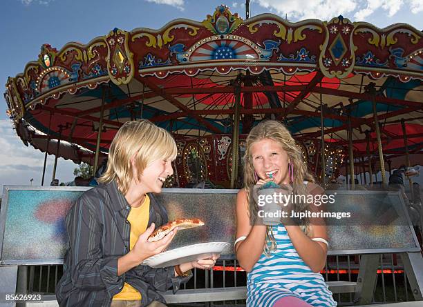 friends eating in front of carousel - スノーコーン ストックフォトと画像