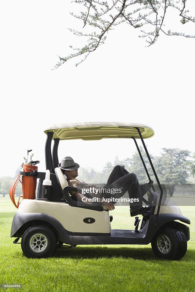 Hipster man napping in golf cart