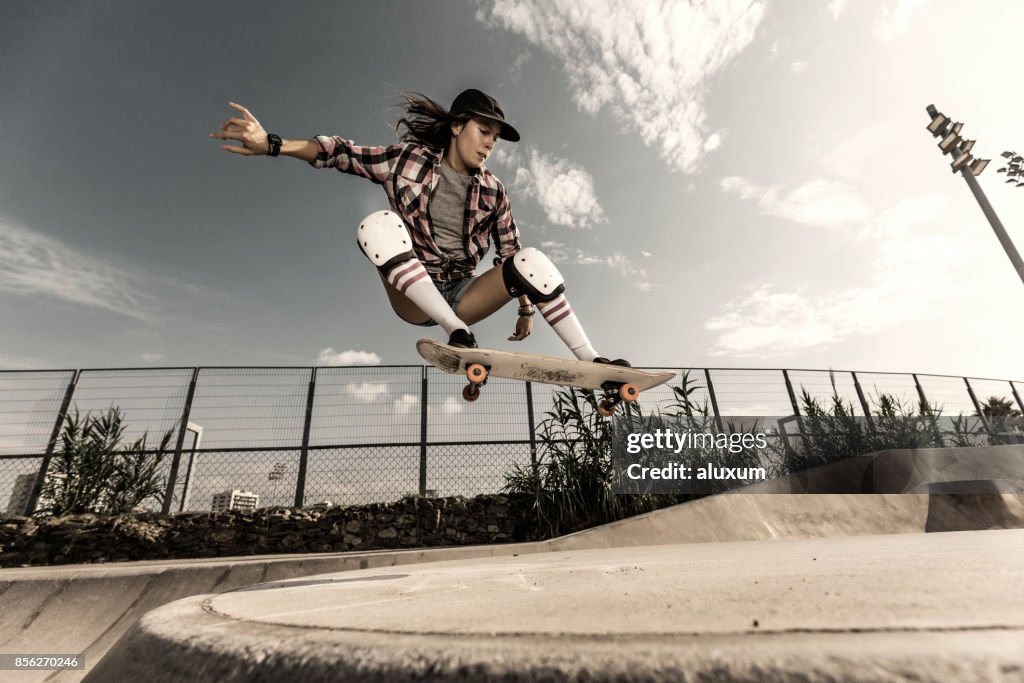 Junge Frau mit Skateboard springen