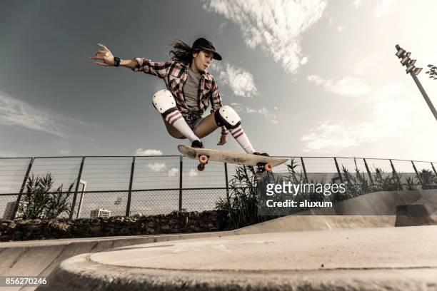 giovane donna che salta con lo skateboard - skate foto e immagini stock