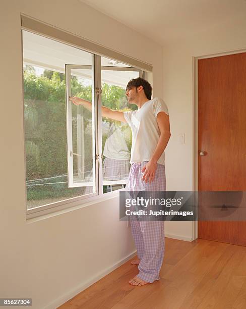 man putting hand out bedroom window - fenster offen stock-fotos und bilder