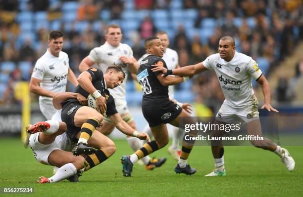 Josh Bassett of Wasps is tackled by Ben Tapuai of Bath during the Aviva Premiership match between Wasps and Bath Rugby at The Ricoh Arena on October...