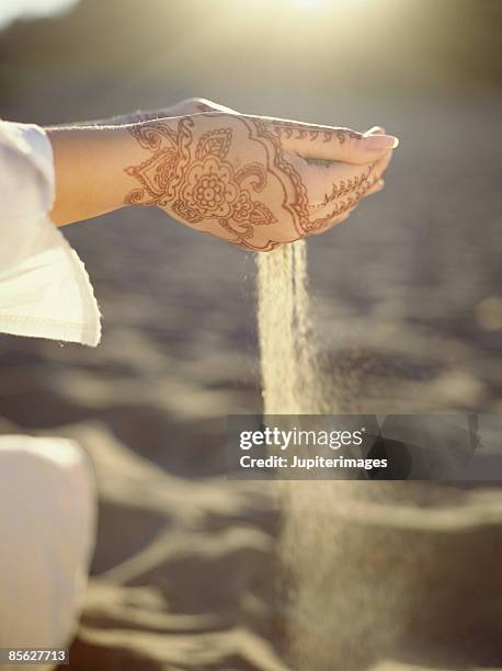 person with hennaed hands holding sand - volatile times stock pictures, royalty-free photos & images