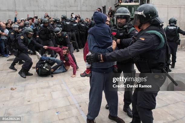 Man and a child holding a red flower run from the police as they move in on the crowds as members of the public gather outside to prevent them from...