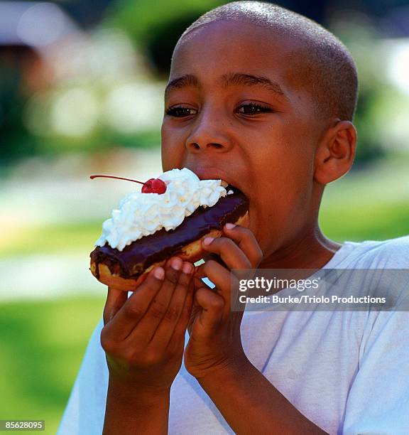 boy eating chocolate eclair - eclair stock pictures, royalty-free photos & images