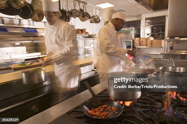 chefs cooking in restaurant kitchen - busy restaurant kitchen stock pictures, royalty-free photos & images