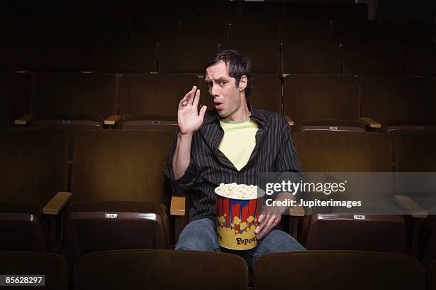 man sitting in movie theater with popcorn - scary movie theatre photos et images de collection