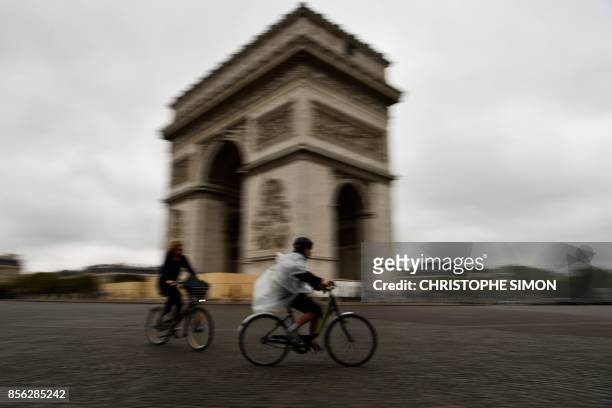 People ride bicycles across the Place de l'Etoile around the Arc de Triomphe monument during a "car free" day in Paris on October 1, 2017. Parisians...