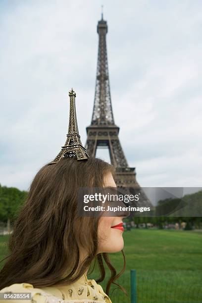 woman balancing model on head near eiffel tower in paris,  france - frankreich souvenir reise stock-fotos und bilder