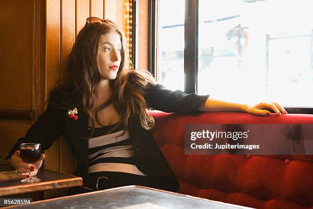 woman in cafe looking out of window - bar paris stockfoto's en -beelden