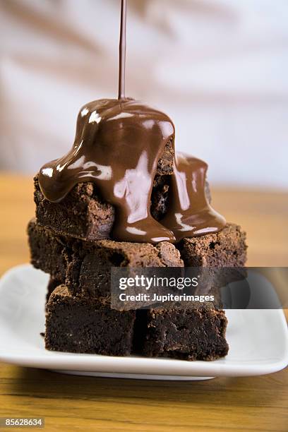 stack of brownies with pouring chocolate - chocoladeglazuur stockfoto's en -beelden