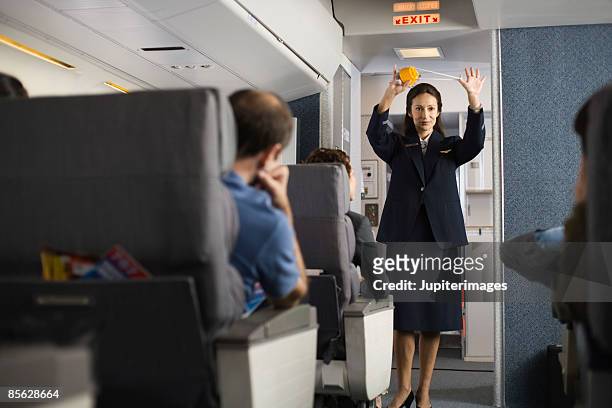stewardess explaining safety procedures to passengers on airplane - stewardess stock-fotos und bilder