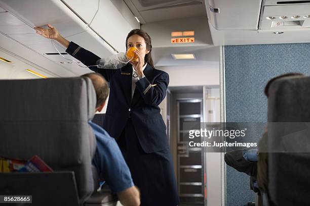 stewardess explaining safety procedures to passengers on airplane - flight attendants stock-fotos und bilder