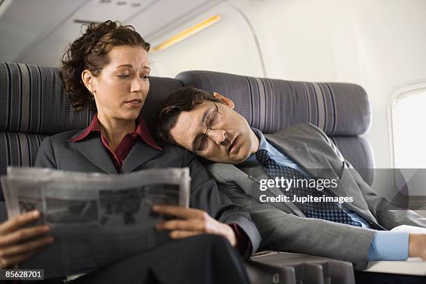 passengers sleeping and reading on airplane - unbehaglich stock-fotos und bilder