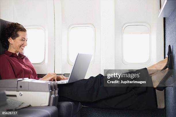 passenger relaxing with laptop computer on airplane - first class flight stock pictures, royalty-free photos & images