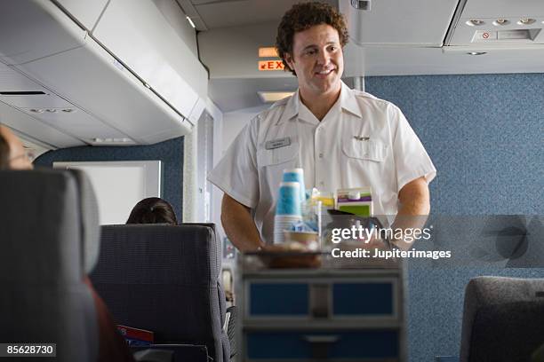 steward serving passengers on airplane - tripulación papel social fotografías e imágenes de stock