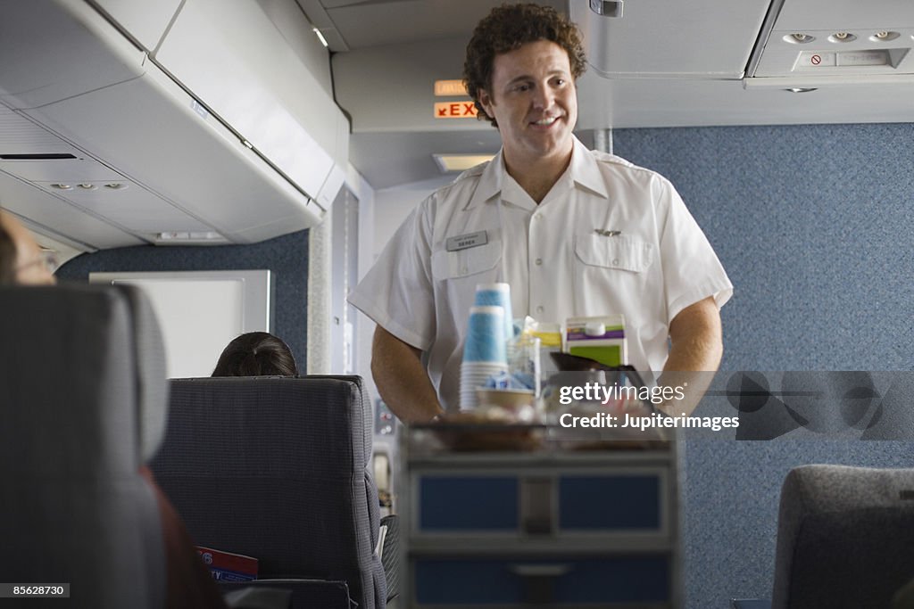 Steward serving passengers on airplane