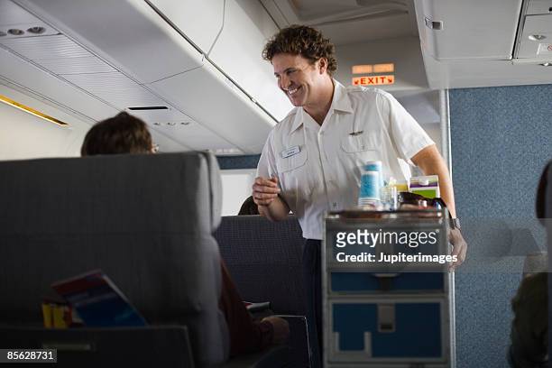 steward serving passengers on airplane - male flight attendant bildbanksfoton och bilder