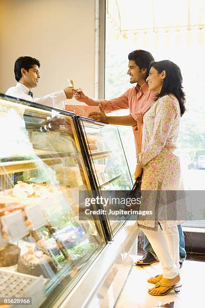 couple buying food from takeout counter - indian dessert stock-fotos und bilder