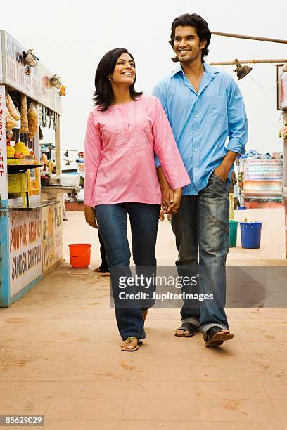 couple holding hands and walking past food stalls, india - marché de plein air photos et images de collection