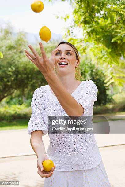 woman juggling lemons - jonglieren stock-fotos und bilder