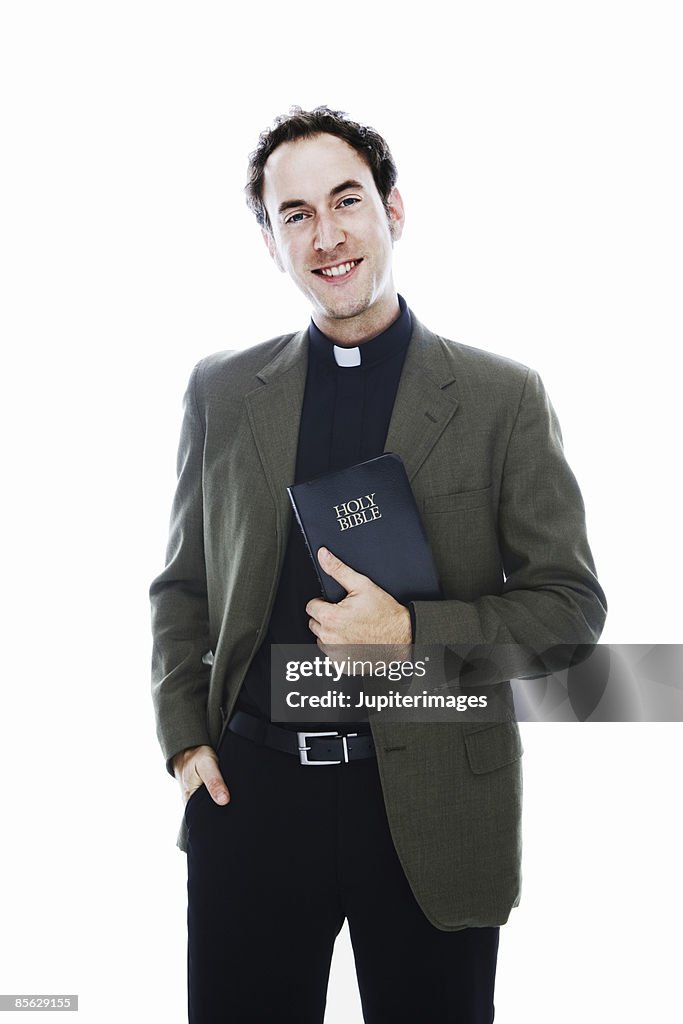 Smiling priest holding bible