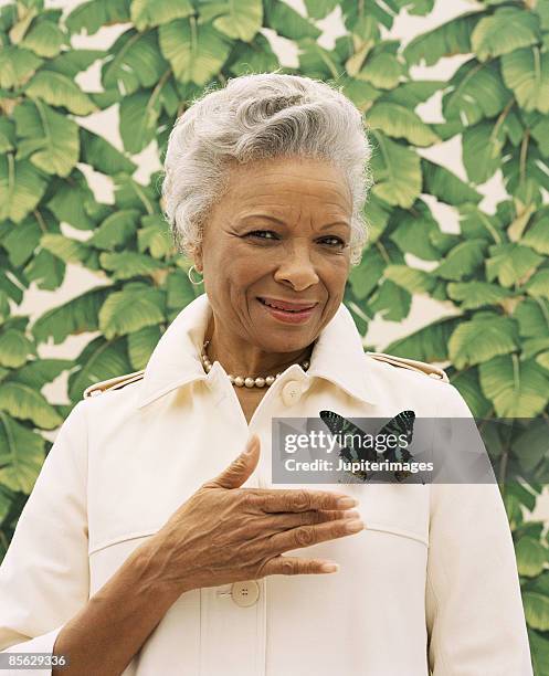 portrait of woman pointing to butterfly pin on jacket - broche stockfoto's en -beelden