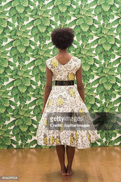 woman standing near leafy wallpaper - black dress stock pictures, royalty-free photos & images