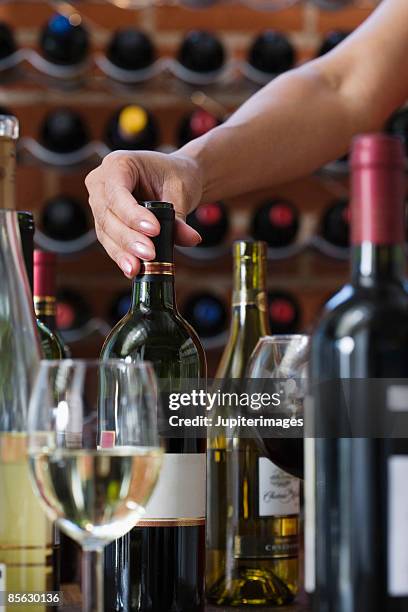 hand with wine bottles and glass - choosing wine stock pictures, royalty-free photos & images