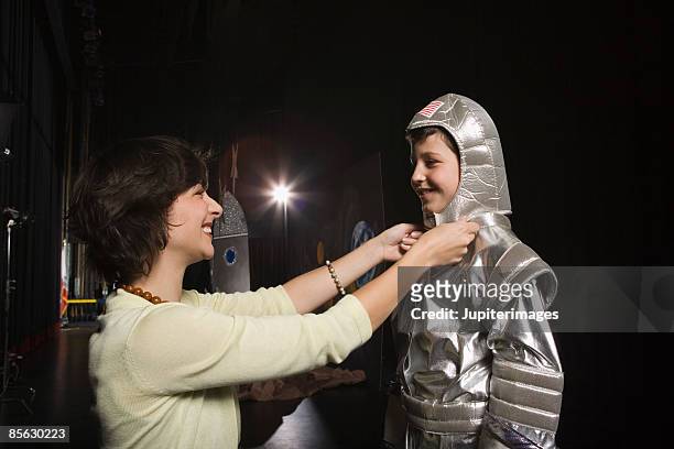 woman putting astronaut costume on child - bühnenkostüm stock-fotos und bilder
