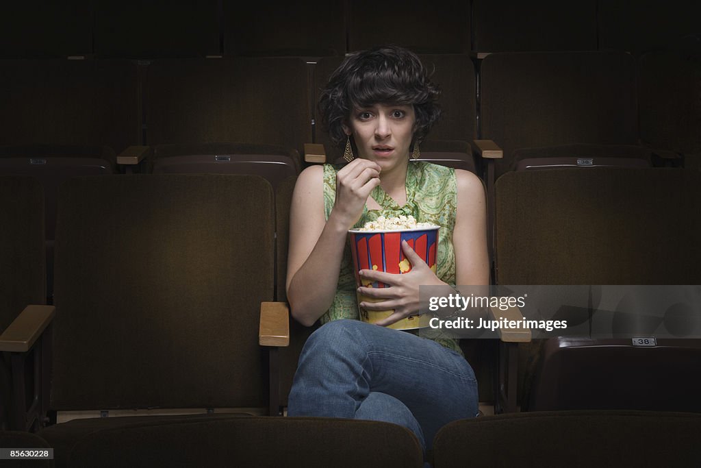Scared woman sitting in movie theatre
