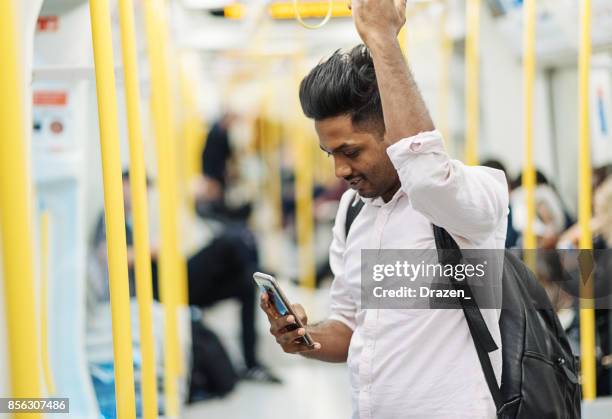 s-bahn mit indischen mann, der smartphone unterwegs verwenden ist - decoding the beauty of time stock-fotos und bilder