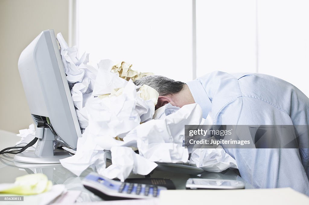 Businessman face down in paper pile