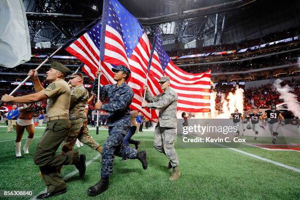 Armed forces members lead the Atlanta Falcons out of the tunnel prior to the game against the Buffalo Bills at Mercedes-Benz Stadium on October 1,...