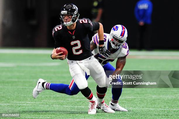 Matt Ryan of the Atlanta Falcons avoids a tackle by Ramon Humber of the Buffalo Bills during the first half at Mercedes-Benz Stadium on October 1,...