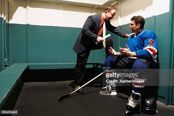 hockey player in locker room with coach - hockey coach stock pictures, royalty-free photos & images
