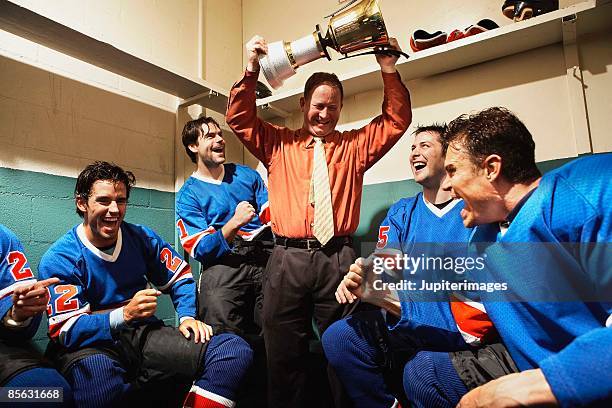 hockey team and coach in locker room with trophy - hockey coach stock pictures, royalty-free photos & images