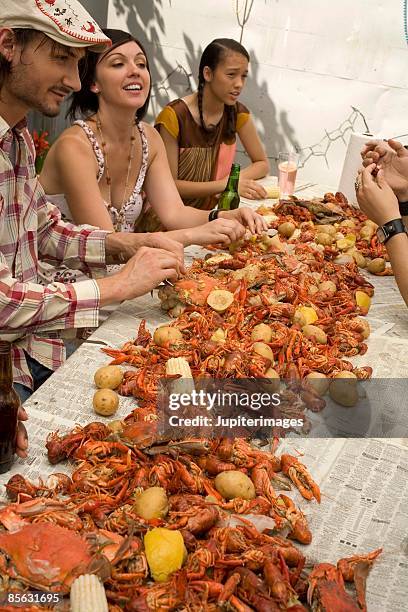 friends eating at seafood boil - flusskrebs meeresfrüchte stock-fotos und bilder