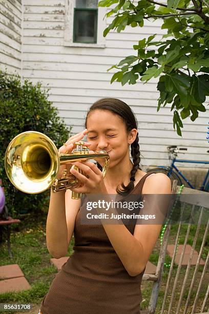 teenage girl playing trumpet - blaasinstrument stockfoto's en -beelden